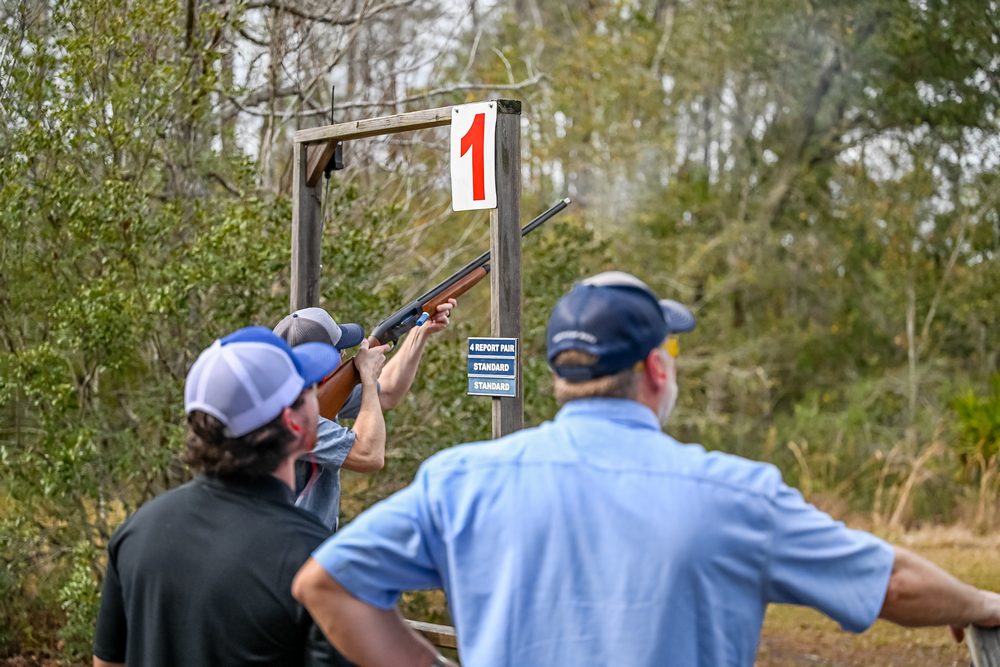 A group at an outdoor range with an instructor at the shooting stand